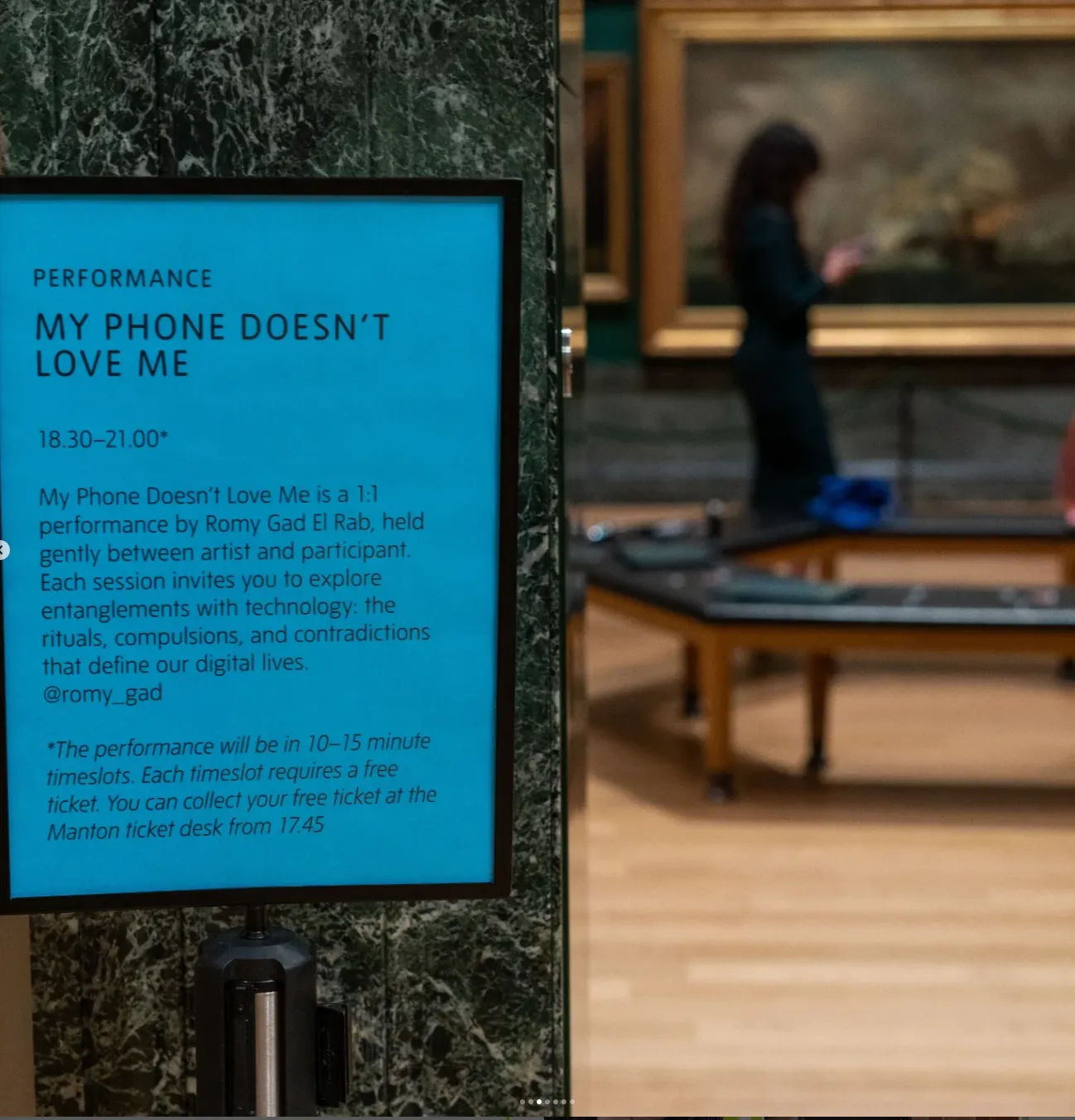 Soft focus long-distance shot of Romy Gad el Rab taken at Tate Britain in 2025 during her event called My phone doesn’t love me, where Romy hosted a 1:1 performance with members of the public to explore the rituals, compulsions, and contradictions of our digital lives.