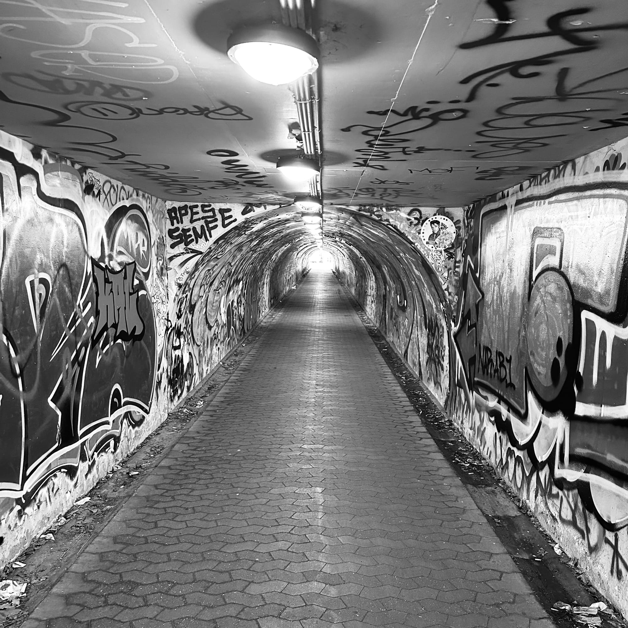 Concrete foot tunnel in Copenhagen covered in graffiti.
