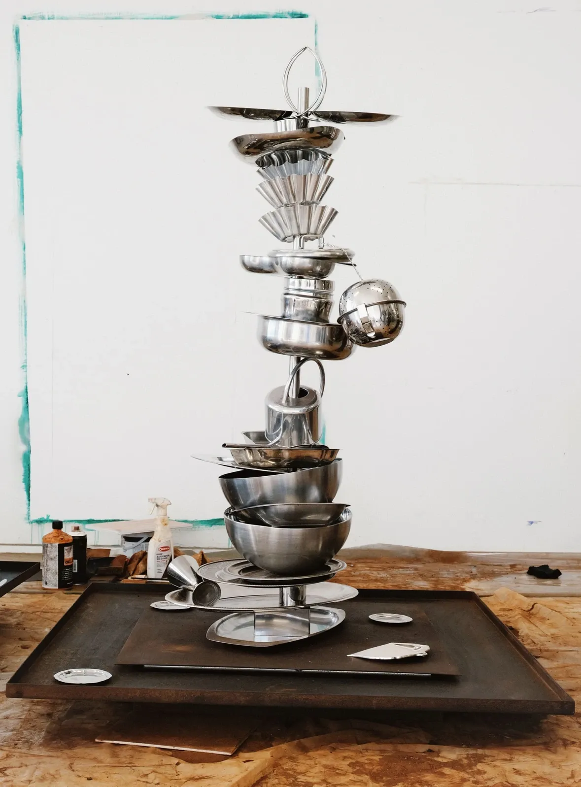 Privilege of Fake Abundance, an artwork by Nicole Vindel which is a precarious stack of metal kitchenware in artist's studio.