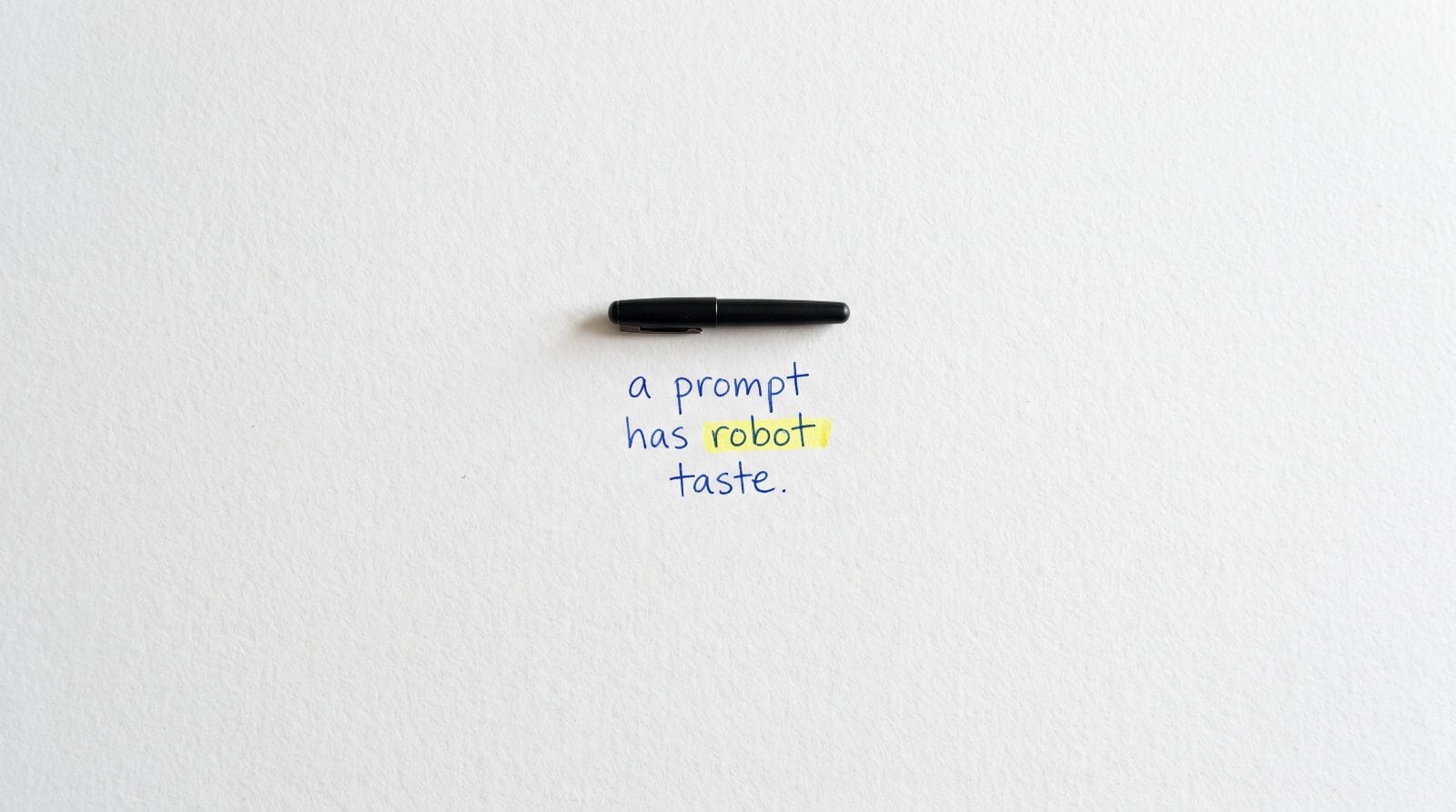 A capped black pen on white paper with the handwritten words: a prompt has robot taste. The word robot is highlighted.