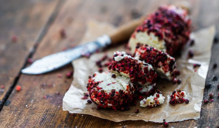 Pink peppercorn crusted macadamia nut cheese on parchment paper