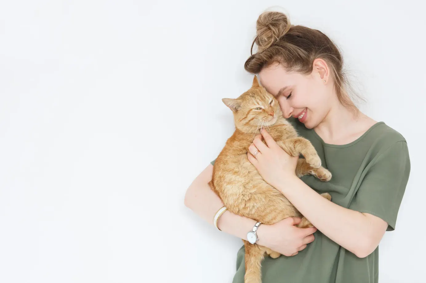 Une femme et un chat roux se font un câlin. 