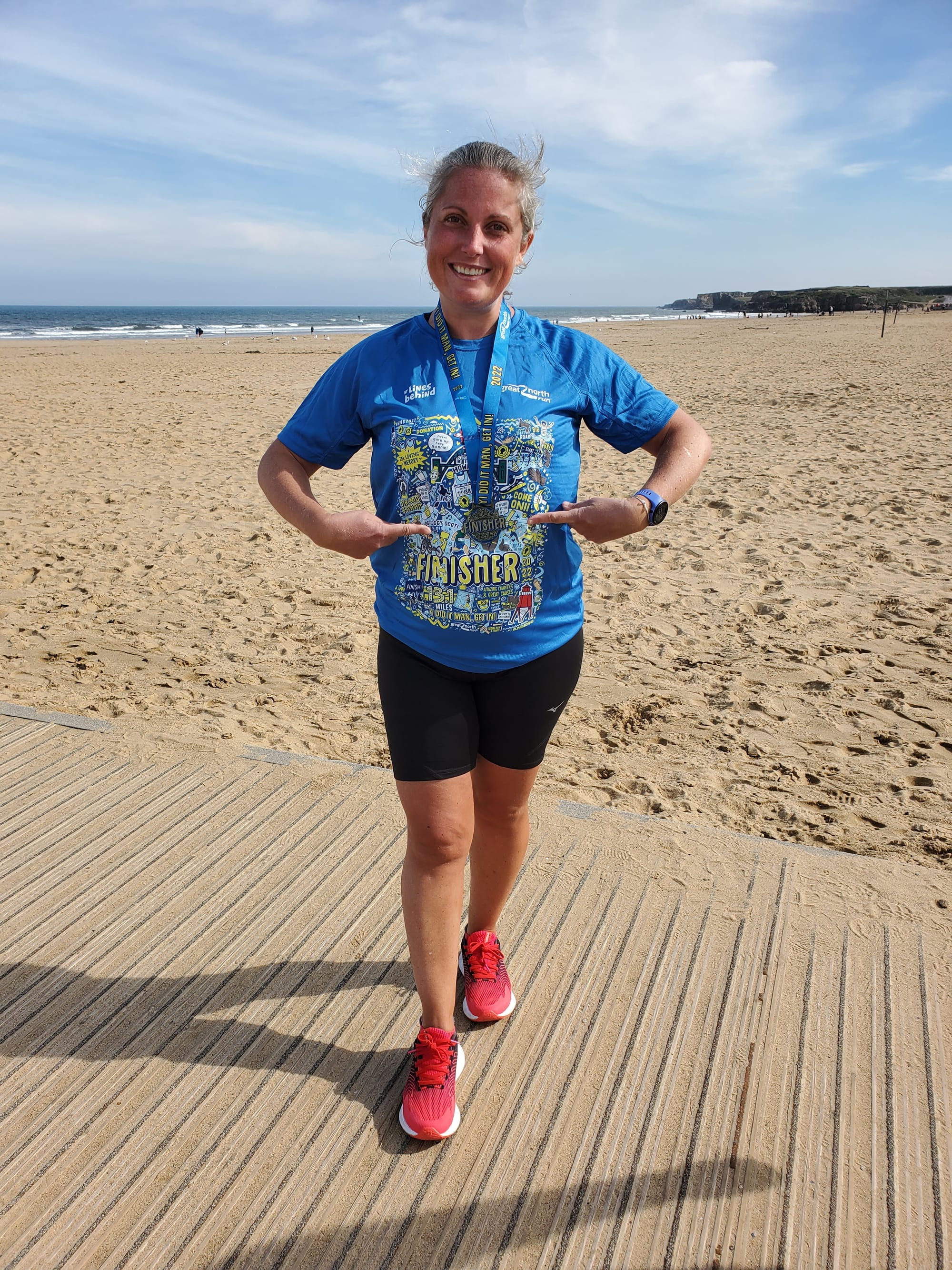 Picture of me on South Shields Beach, pointing at my Great North Run Finisher's medal. 