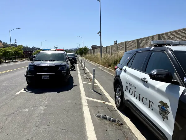 Richmond police patrol vehicles parked along a road next to a protected bike lane and sound wall.