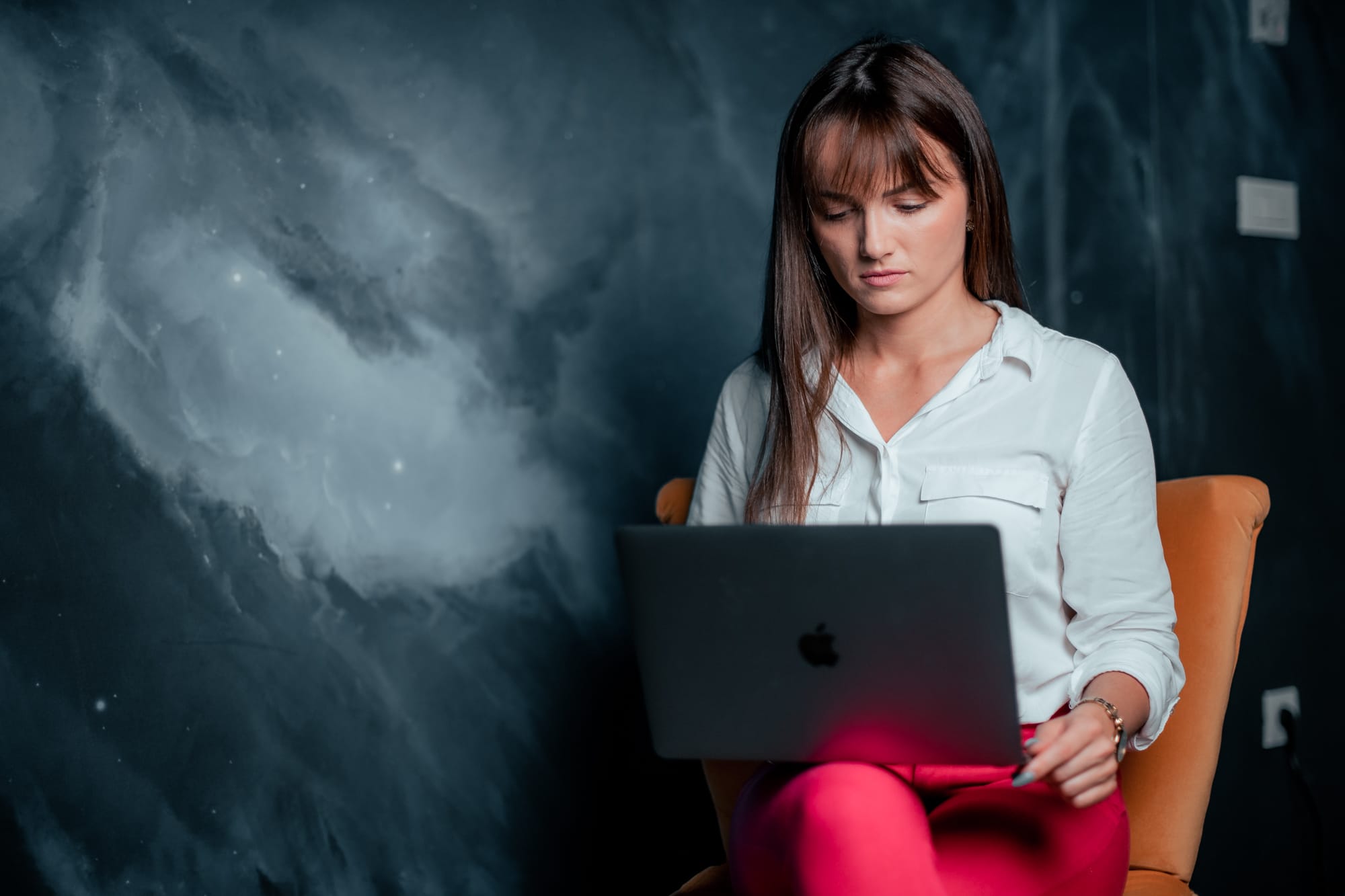 Software developer focused on a laptop, working in a digital product studio with a galaxy-themed background.