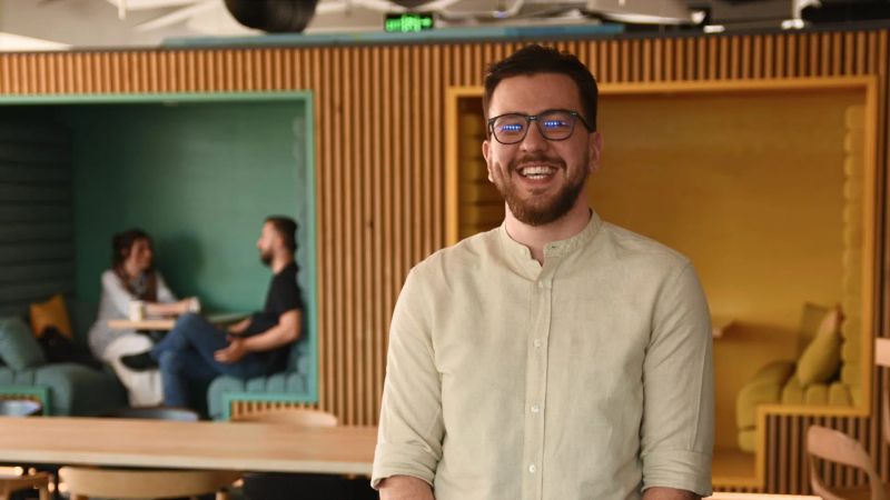 Product designer standing in a collaborative workspace.