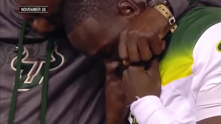 In a screencap from the broadcast, USF quarterback Quinton Flowers is wearing a green and white football jersey, and being e