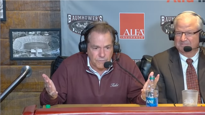 Nick Saban sits at a desk gesturing angrily during his radio show 