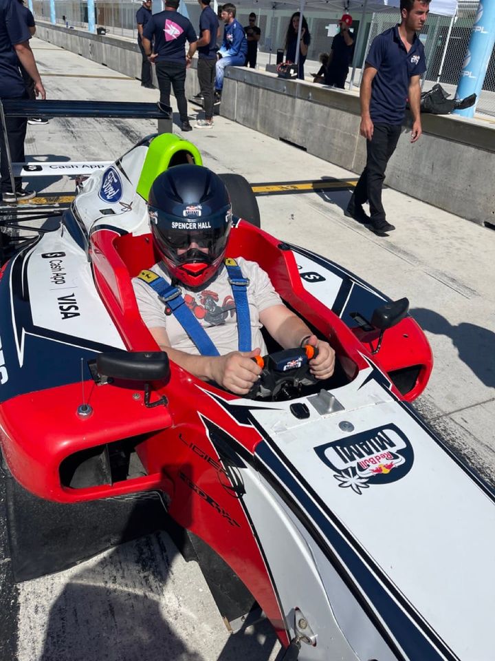 A bear sitting in an Formula Four car 