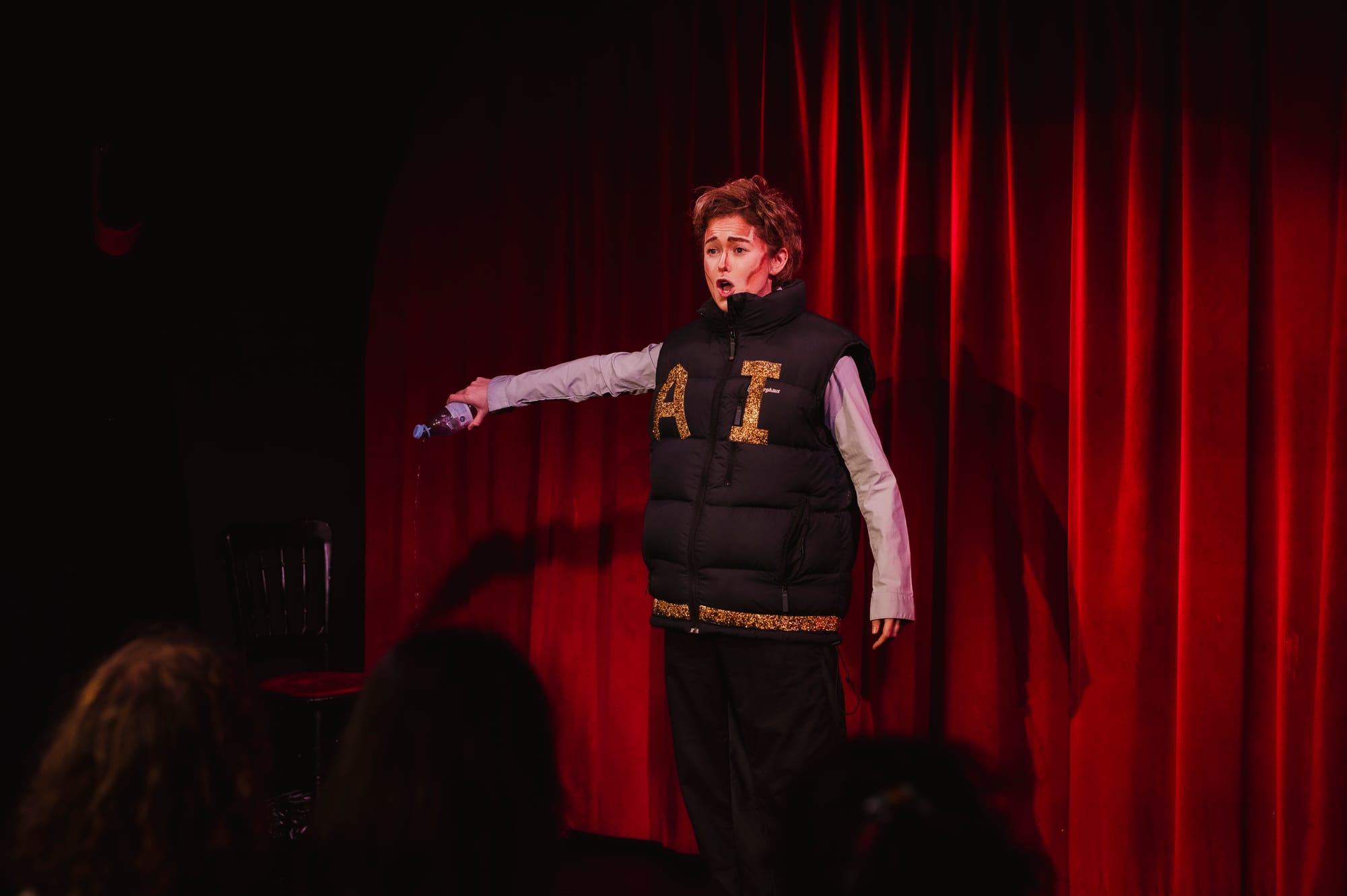 Image of a drag king in a gilet with 'AI' in gold sparkly letters
