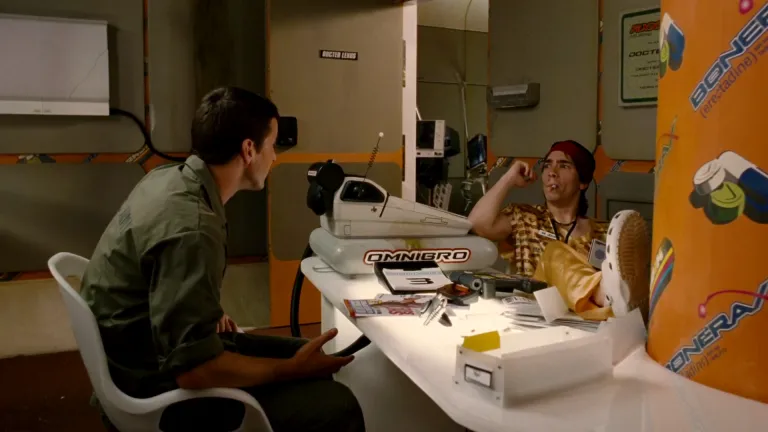 still from the doctor's office scene in the movie "Idiocracy." the computer on his desk is called "OMNIBRO"