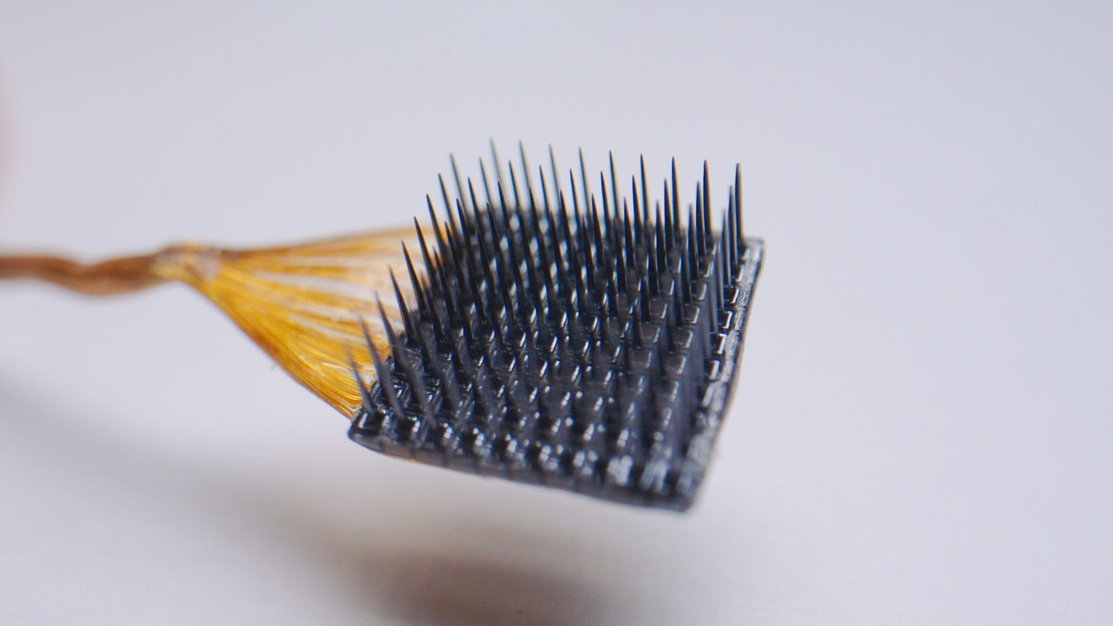 Close-up of the Utah Array showing its grid of silicon microneedle electrodes and gold wire bundle