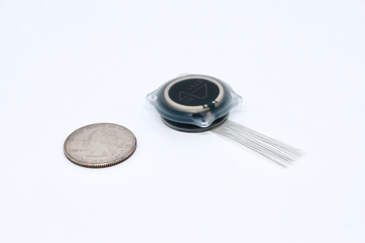 Close-up of Neuralink's N1 implant shown beside a US quarter for scale