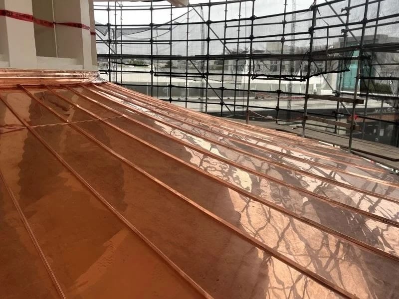 close-up of a shiny copper roof surrounded by scaffolding.