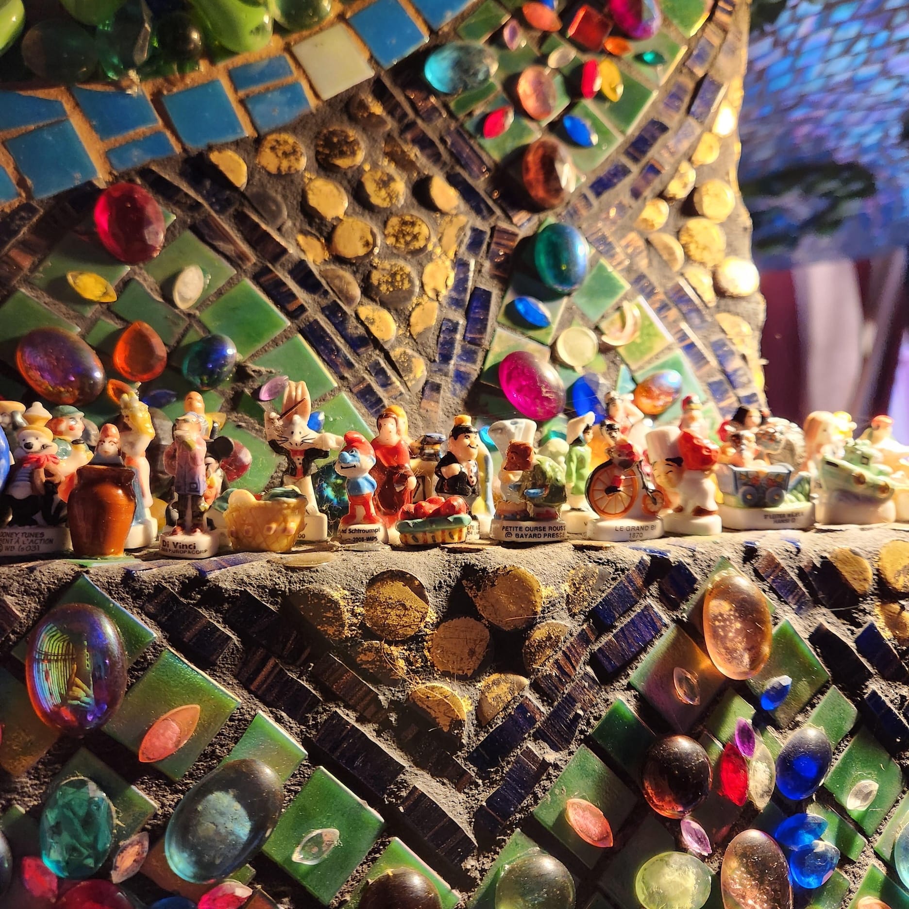 Close-up of a bejeweled column with dozens of tiny figurines on a ledge.