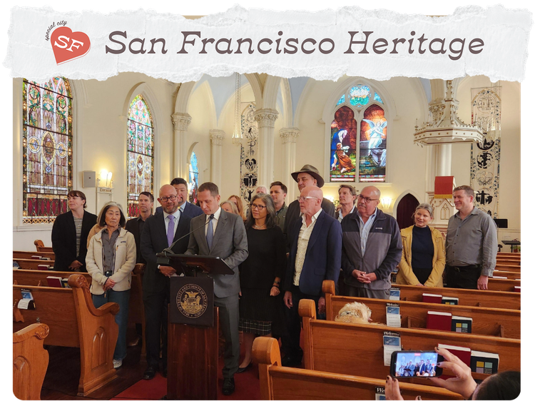 A group of people inside a church with white archways, man in grey suit standing behind a podium featuring seal of the city of San Francisco.