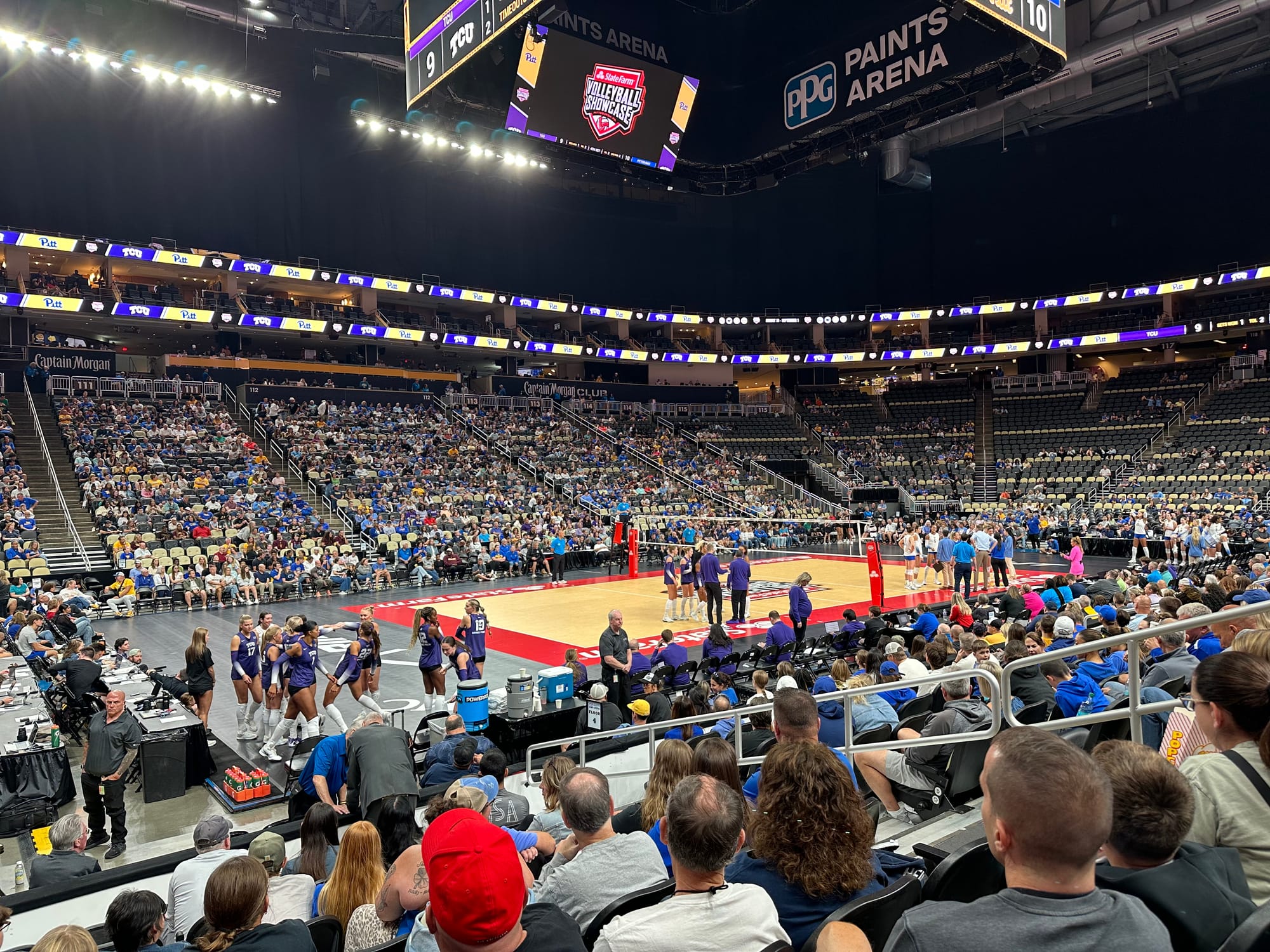 A photograph of the inside of PPG Paints Arena during a volleyball match between Pitt and TCU. The crowd is filling up most, but not all, of the lower bowl