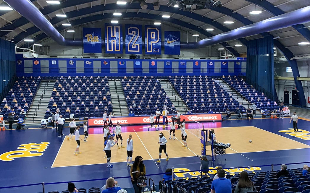 Photo from March of 2021 shows the Pitt Panthers volleyball team warming up in front of a few human fans, but mostly cardboard cutouts of fans in the stands