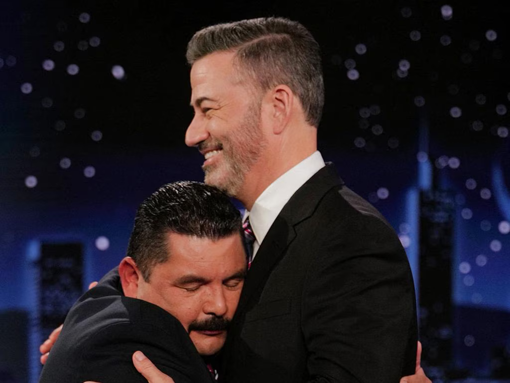 Two men hug in the front of a city skyline