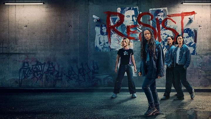 the cast of Gen V standing in front of a wall of posters spray painted with the word RESIST