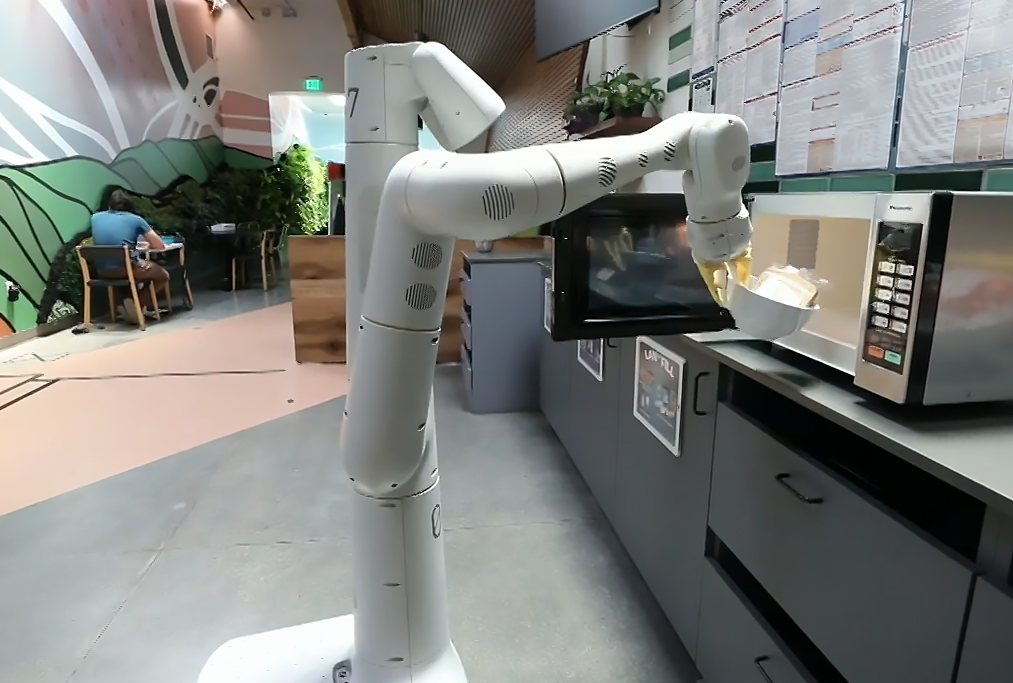 A robot putting something in the microwave