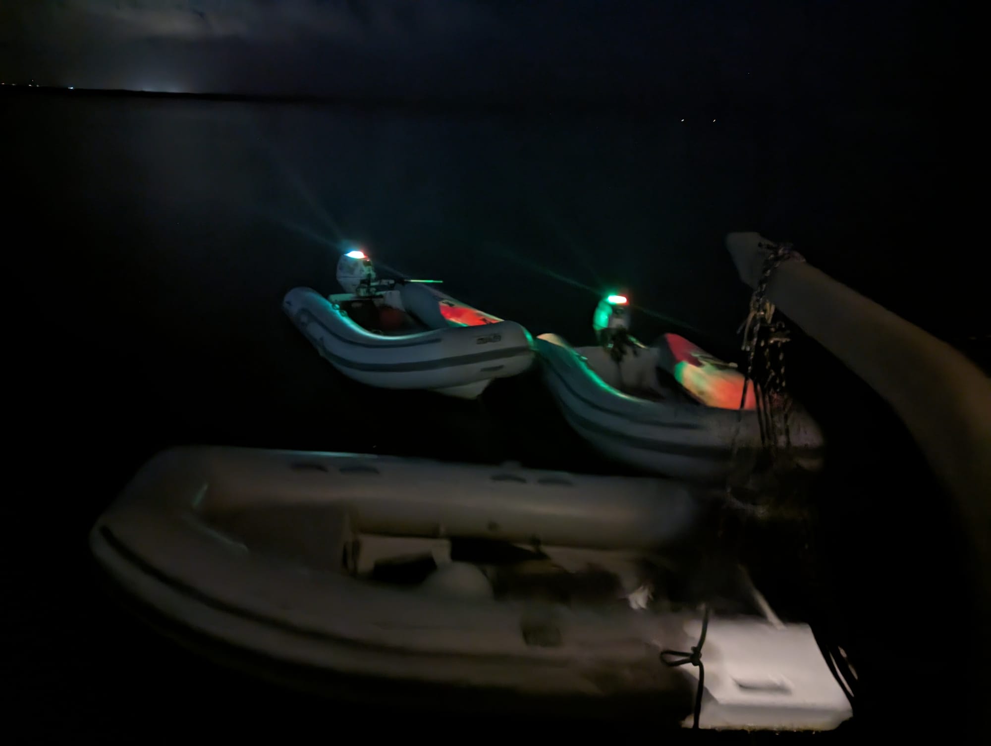 Two dinghies illuminated by Show Me Your Dinghy lights at night
