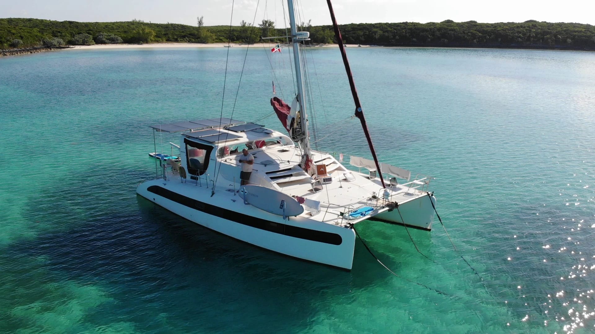 Catamaran anchored in clear turquoise water with the anchor bridle running down toward the chain hook