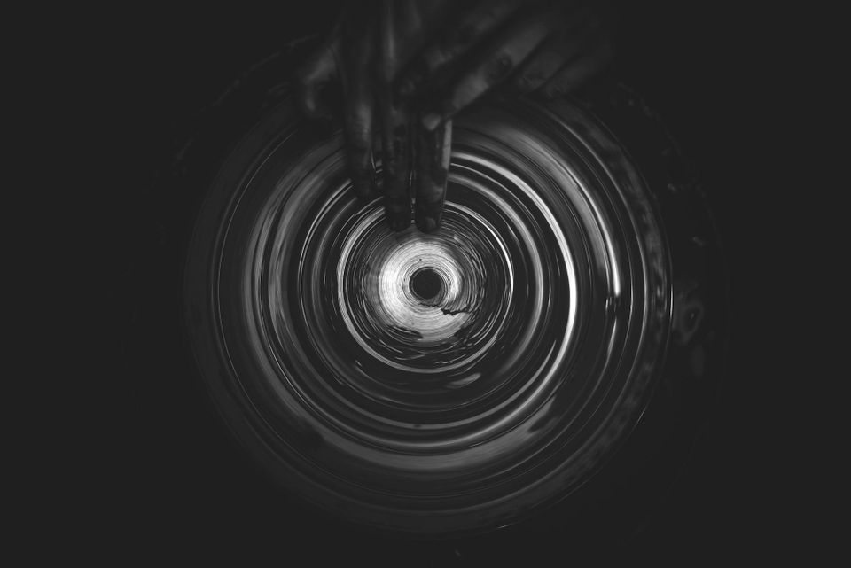 Black and white vortex image with a pair of hands holding the top portion leading into the spin of the spiral.