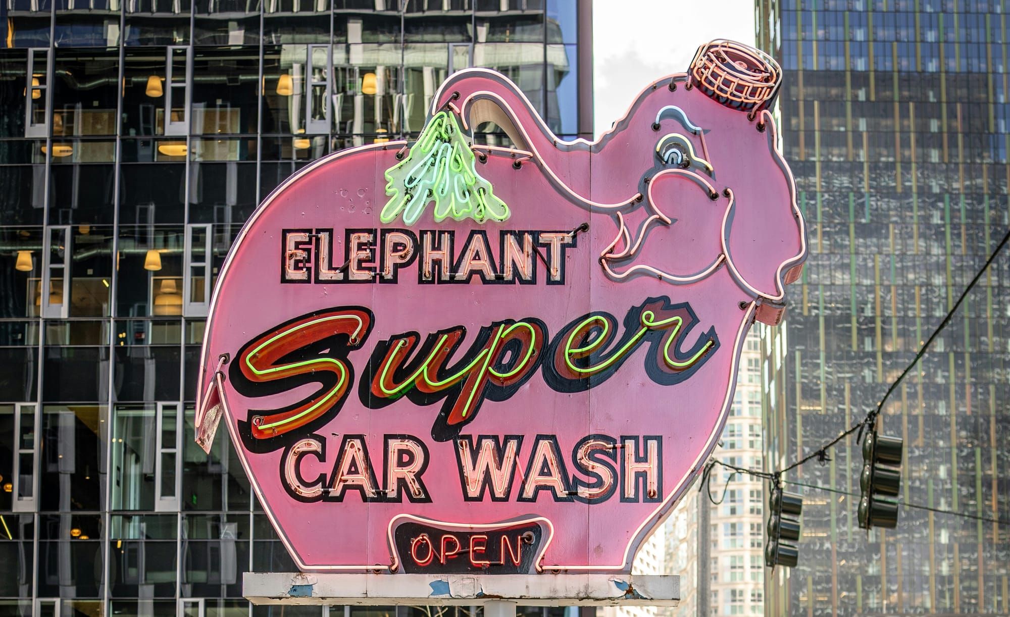 A sign for a car wash in the shape of a pink elephant called 'Elephant Super Car Wash'