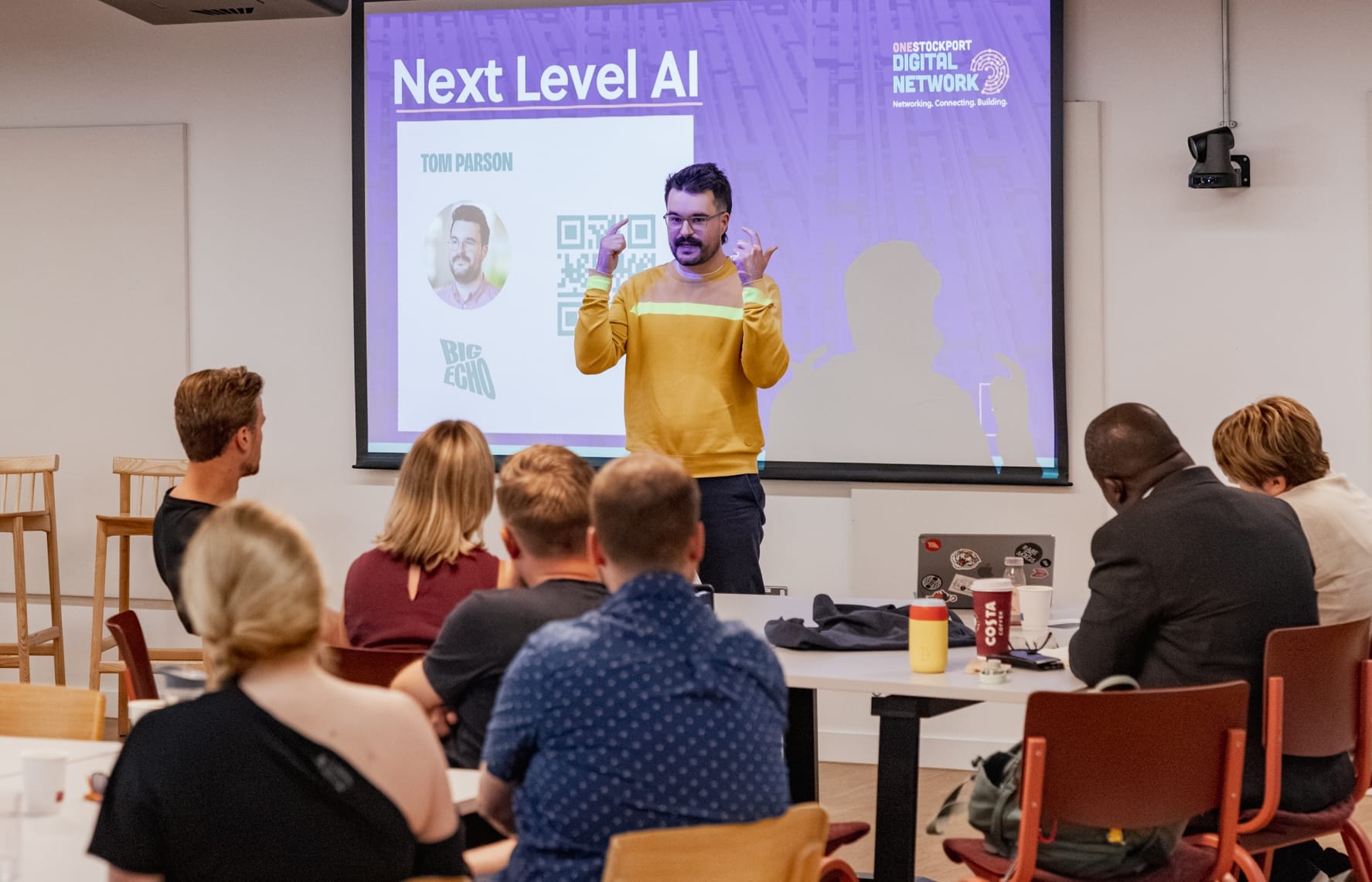 Man standing in front of people speaking.