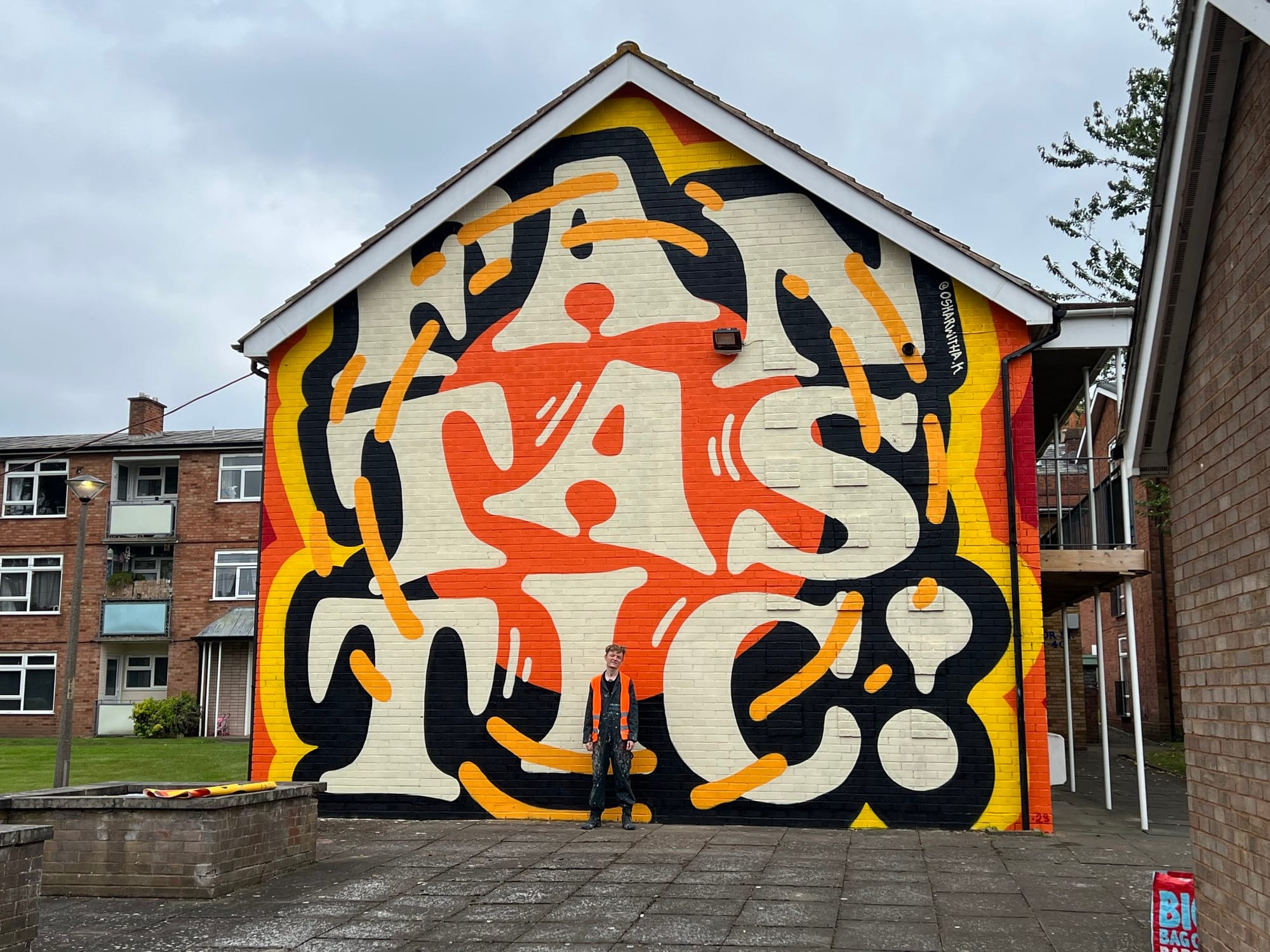 A person standing in front of a vibrant painted side of a building.