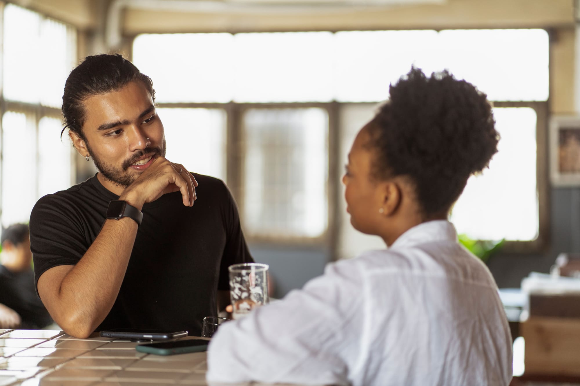 Two people speaking over a drink.