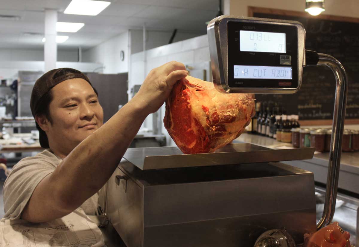 Eddy Shin, owner of A Cut Above Butchers, weighs a piece of grass-fed beef. (Michael Ryan michael@www.smdp.com)