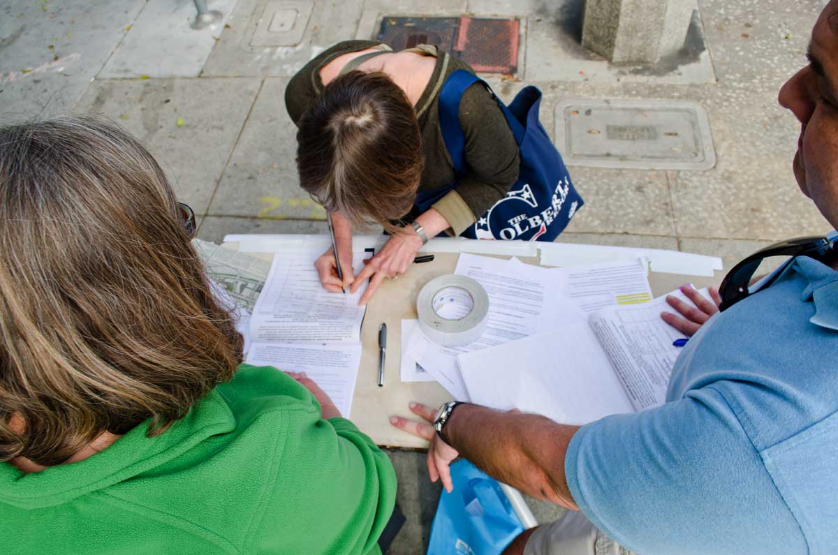 A woman signs a petition during the citywide referendum signing party outside of Surf Liquor on Saturday. Activists are seeking to nix a City Council-approval of a major development on Olympic Boulevard. (Paul Alvarez Jr. editor@www.smdp.com)