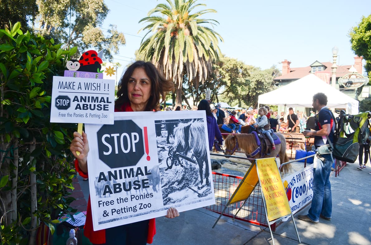 A woman protests against the pony rides and petting zoo at the Farmers' Market on Main Street on Sunday morning. (Paul Alvarez Jr. editor@www.smdp.com)