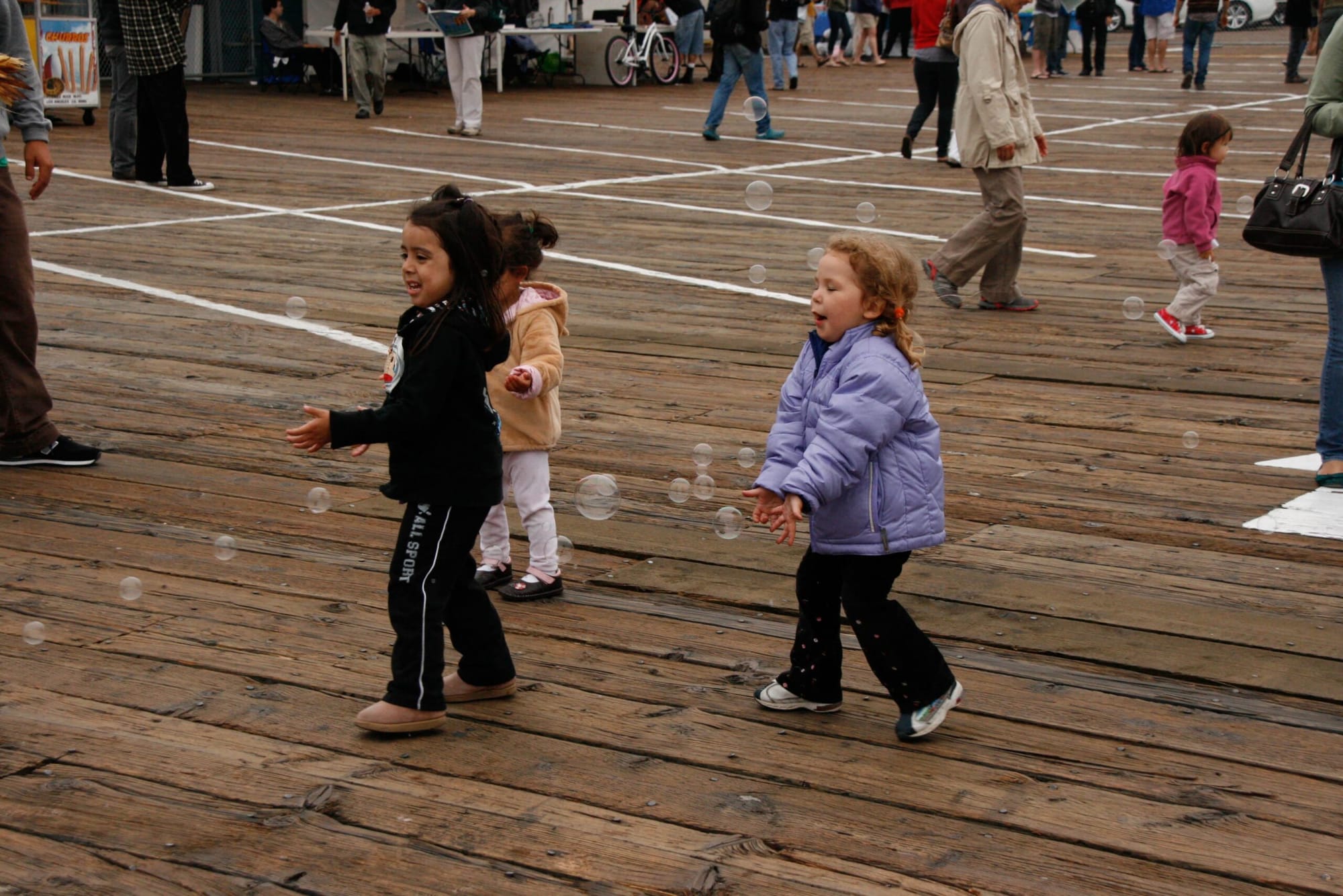 Children at the Santa Monica Pier enjoy playing with floating bubbles. (File photo)
