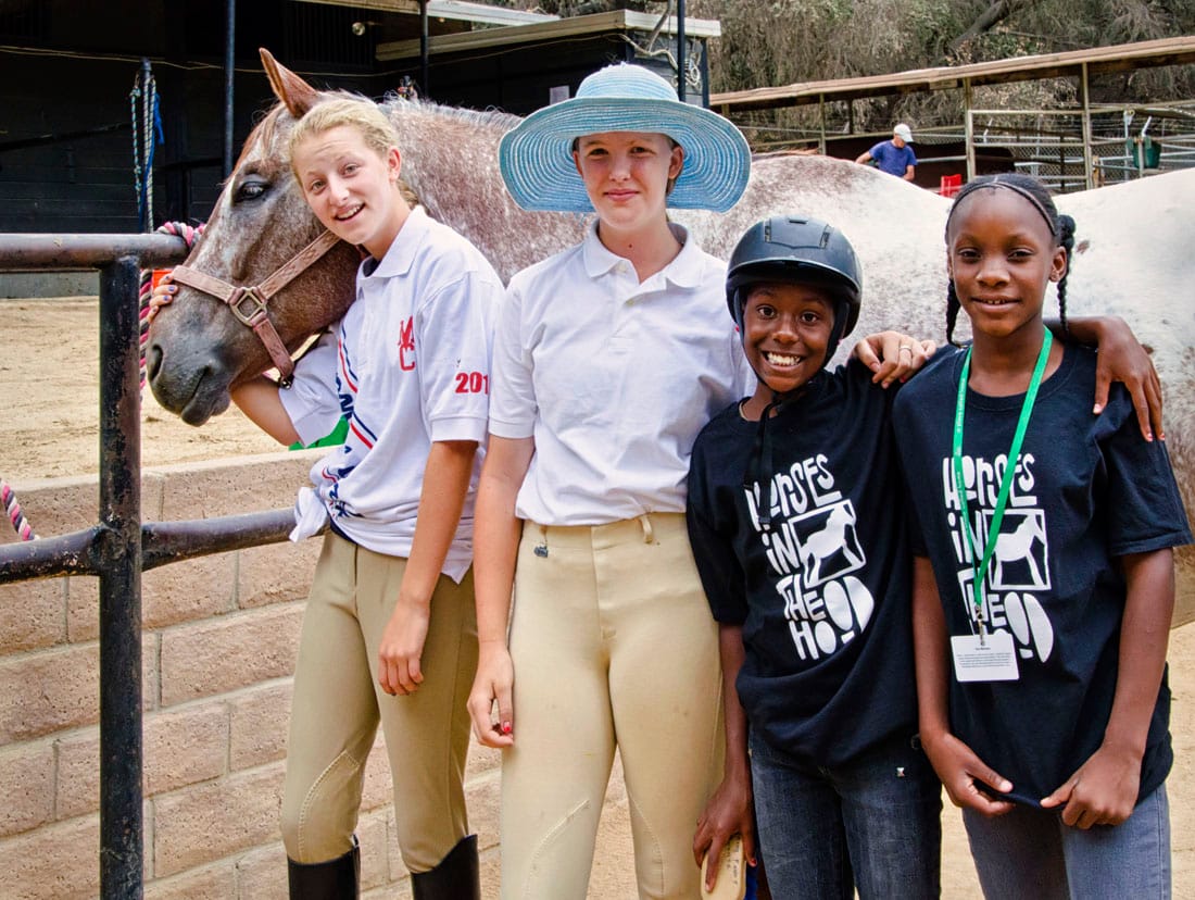 HAPPY CAMPERS: Horses in the Hood volunteers Gizelle Whaley (left) and India Whitecloud have fun teaching the kids enrolled in the program that introduces them to horses. (Photo courtesy Vivian Nagy)