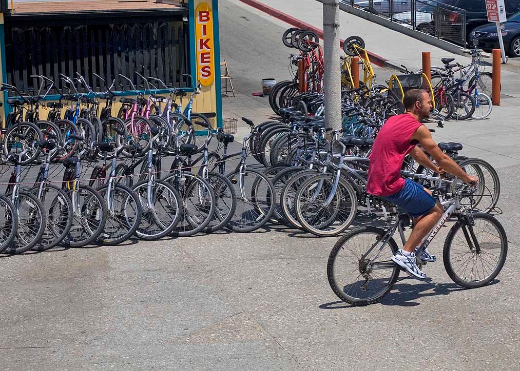 WHEELS FOR DAYS: A man rides his bike past a popular bicycle rental shop near the foot of the Santa Monica Pier. (File photo)