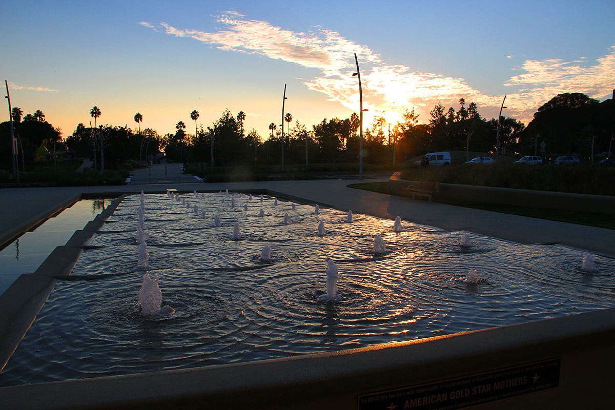 The fountain at Ken Genser Square in front of City Hall reflects the sunset.