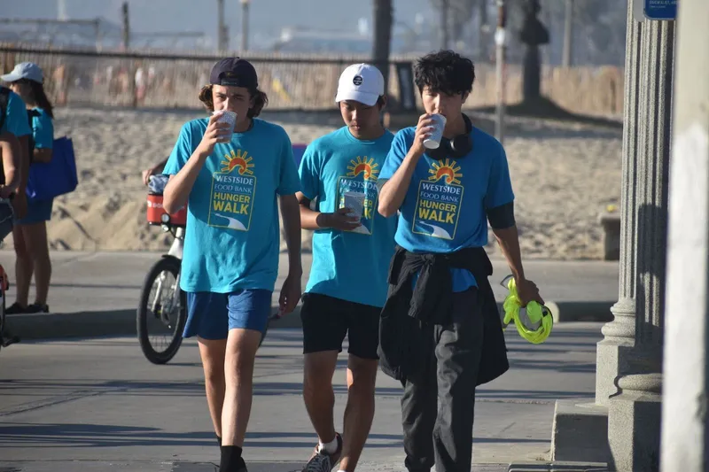 A group of people in blue t-shirts walks by the beach in Santa Monica.