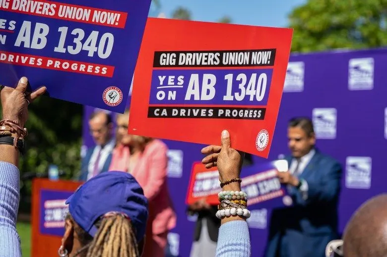 A close-up view of a person holding a sign at a rally that reads 