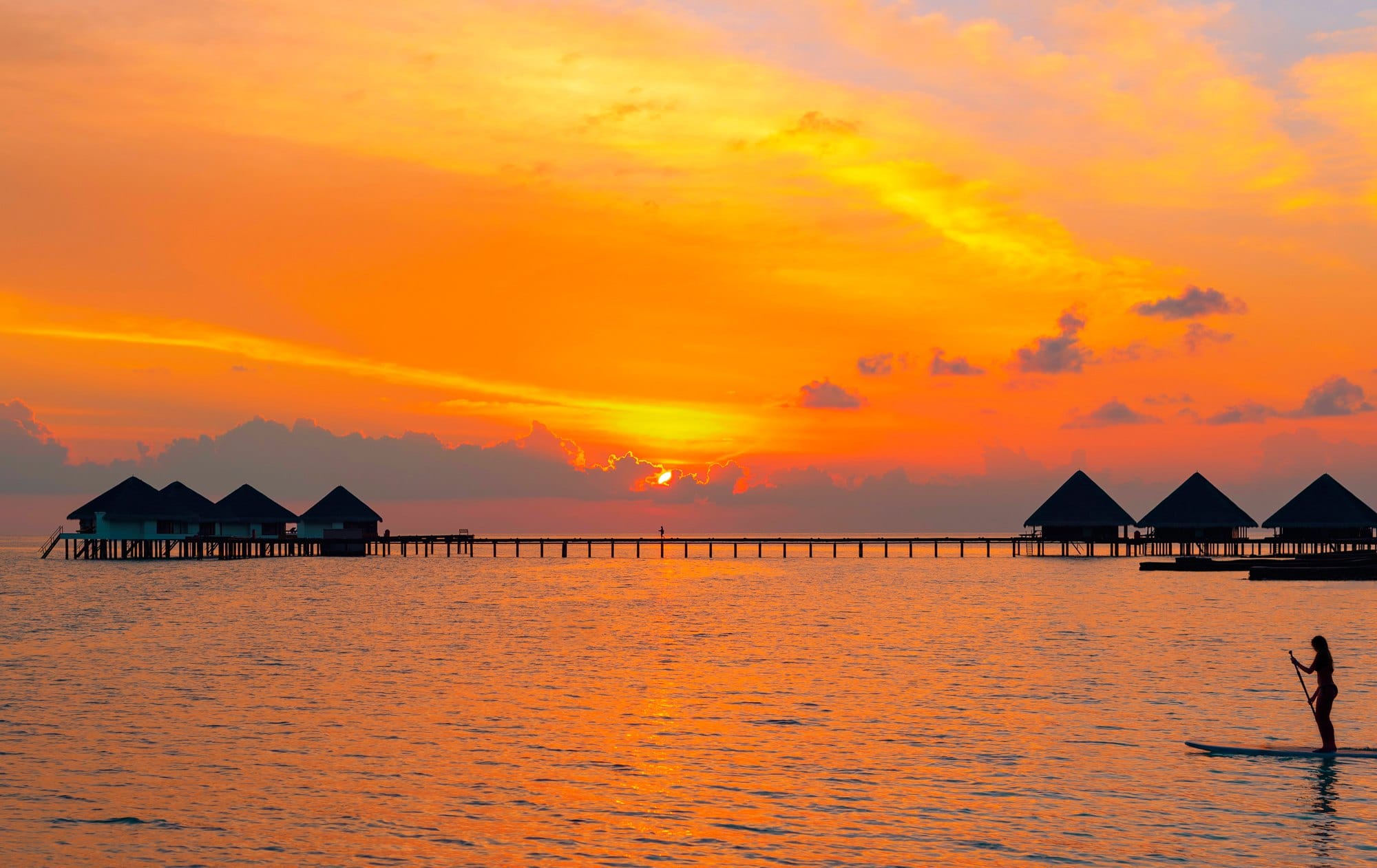 A Picturesque Sunset In The Maldives And The Silhouette Of A Girl Floating On A Paddle Board