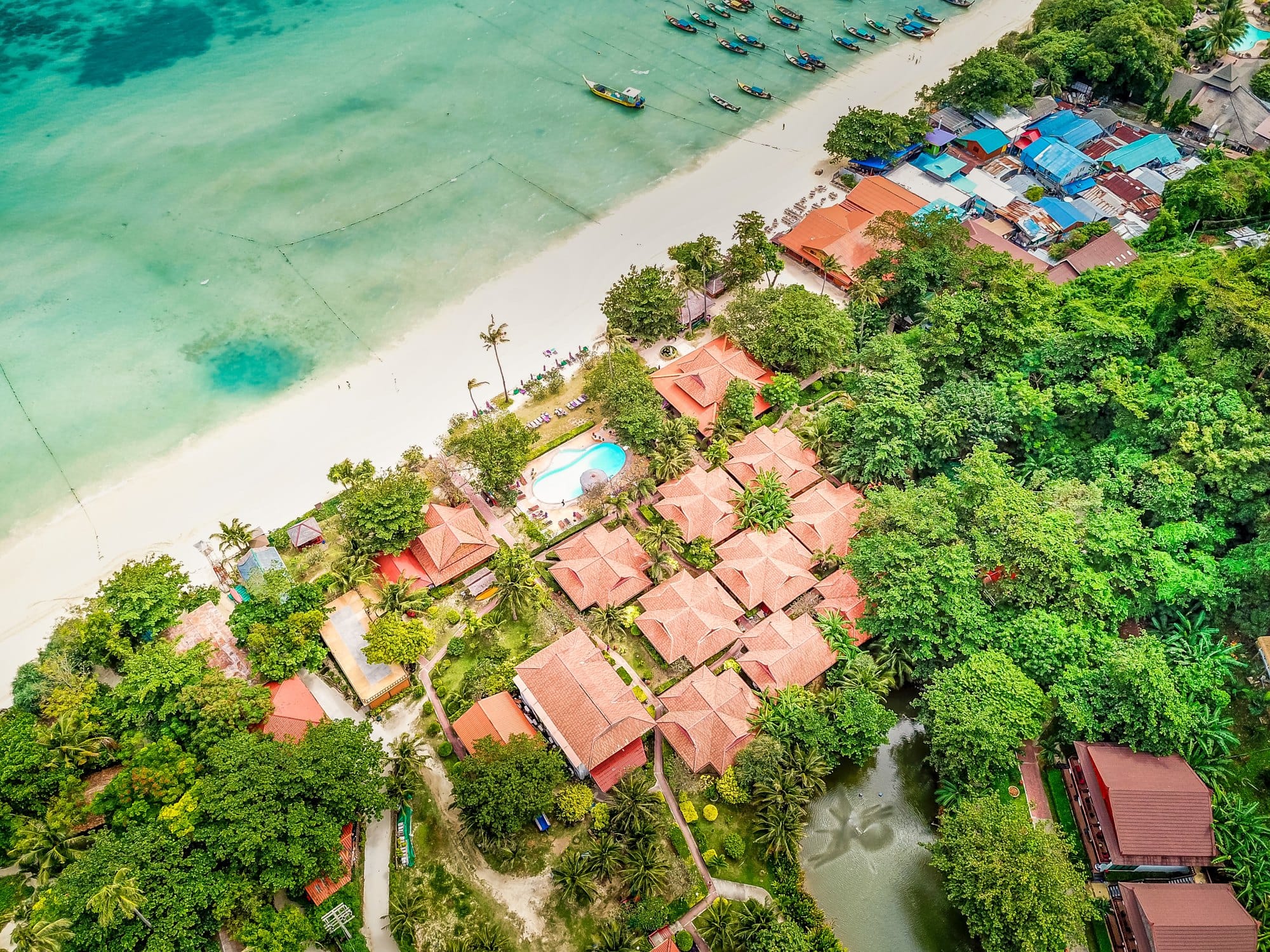 Aerial view of a luxury hotel surrounded by dense trees in Phi Phi island, Thailand
