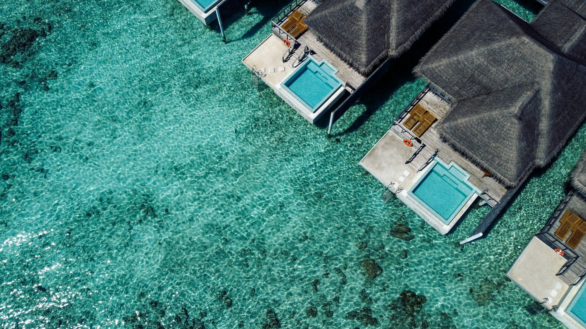 Aerial view of luxurious overwater villas with thatched roofs