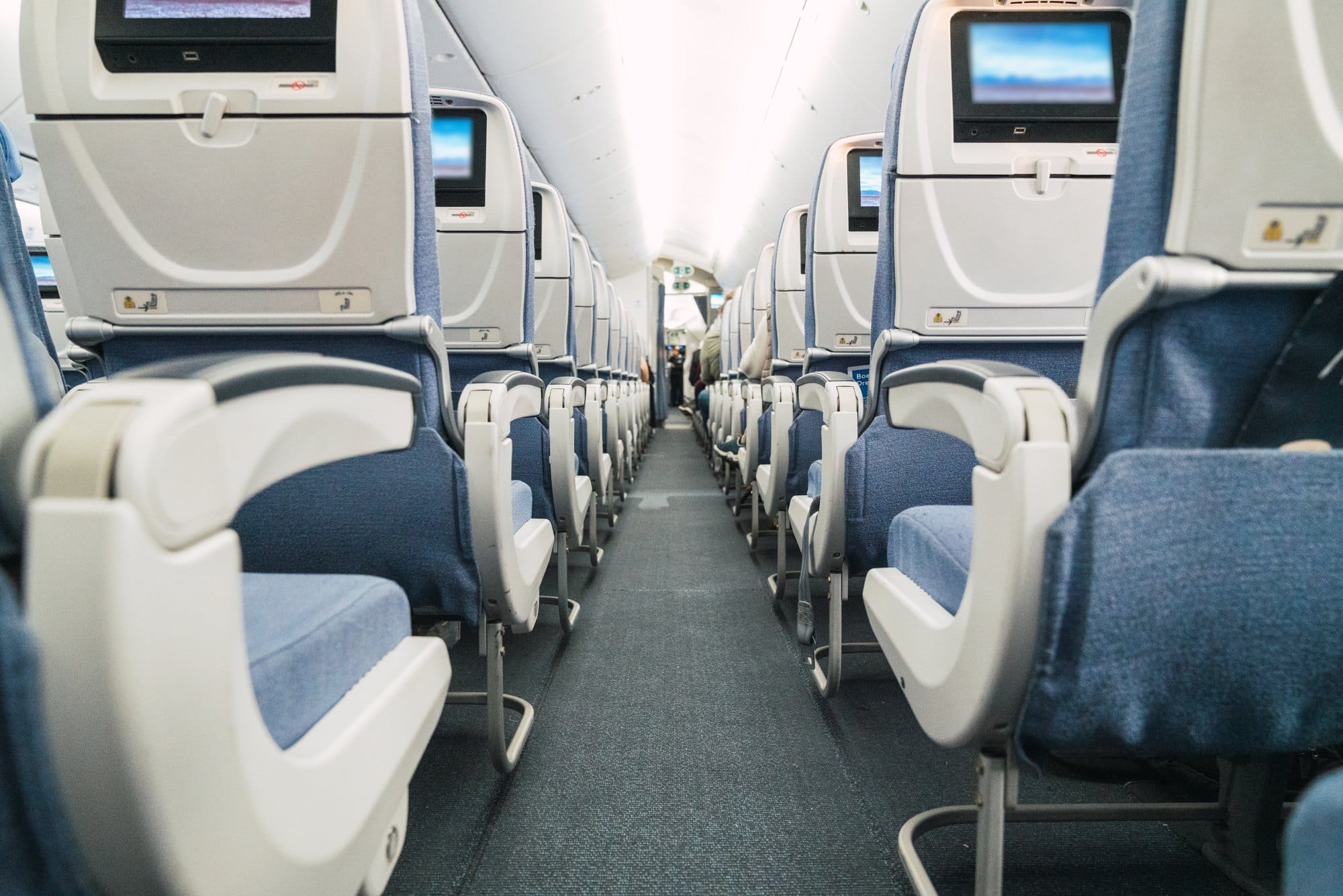 Airplane Interior Featuring Blue Seats and Television Screens