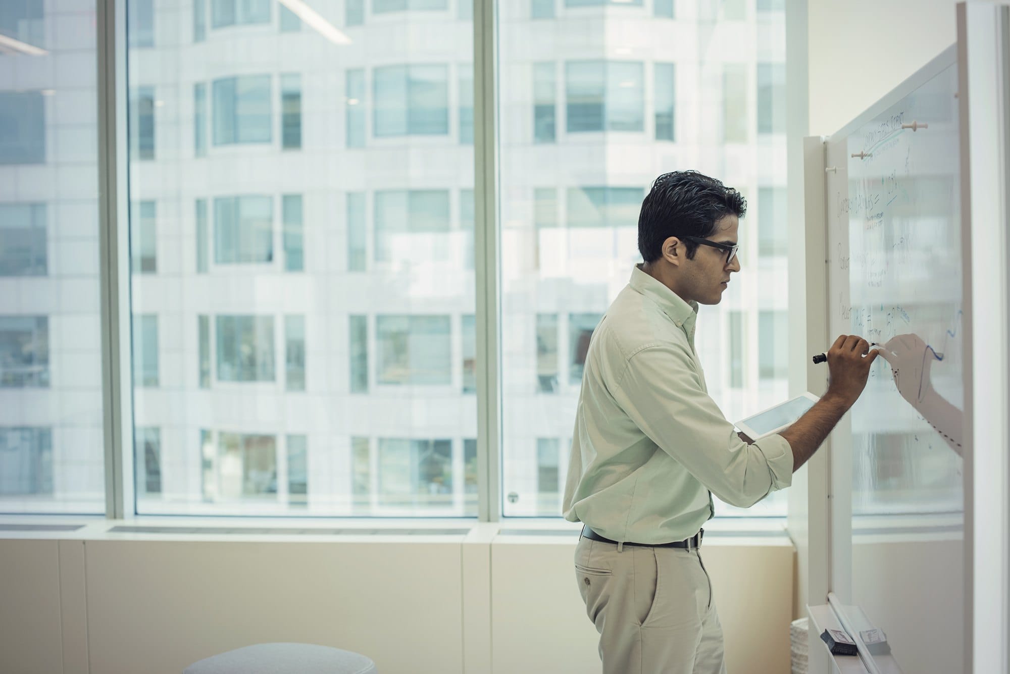 Businessman in office writing on whiteboard