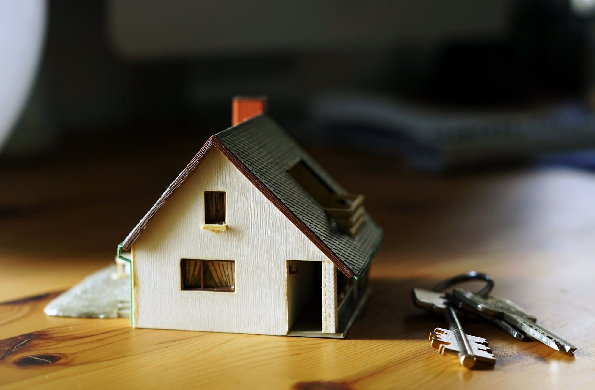 Closeup of a miniature house with keys on the table - Real estate concept