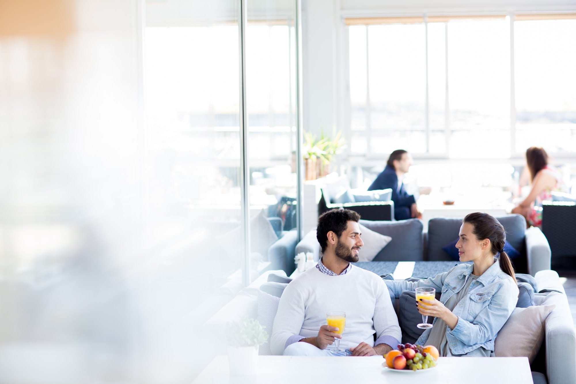 Couple Relaxing on Sofa with Drinks in Lounge