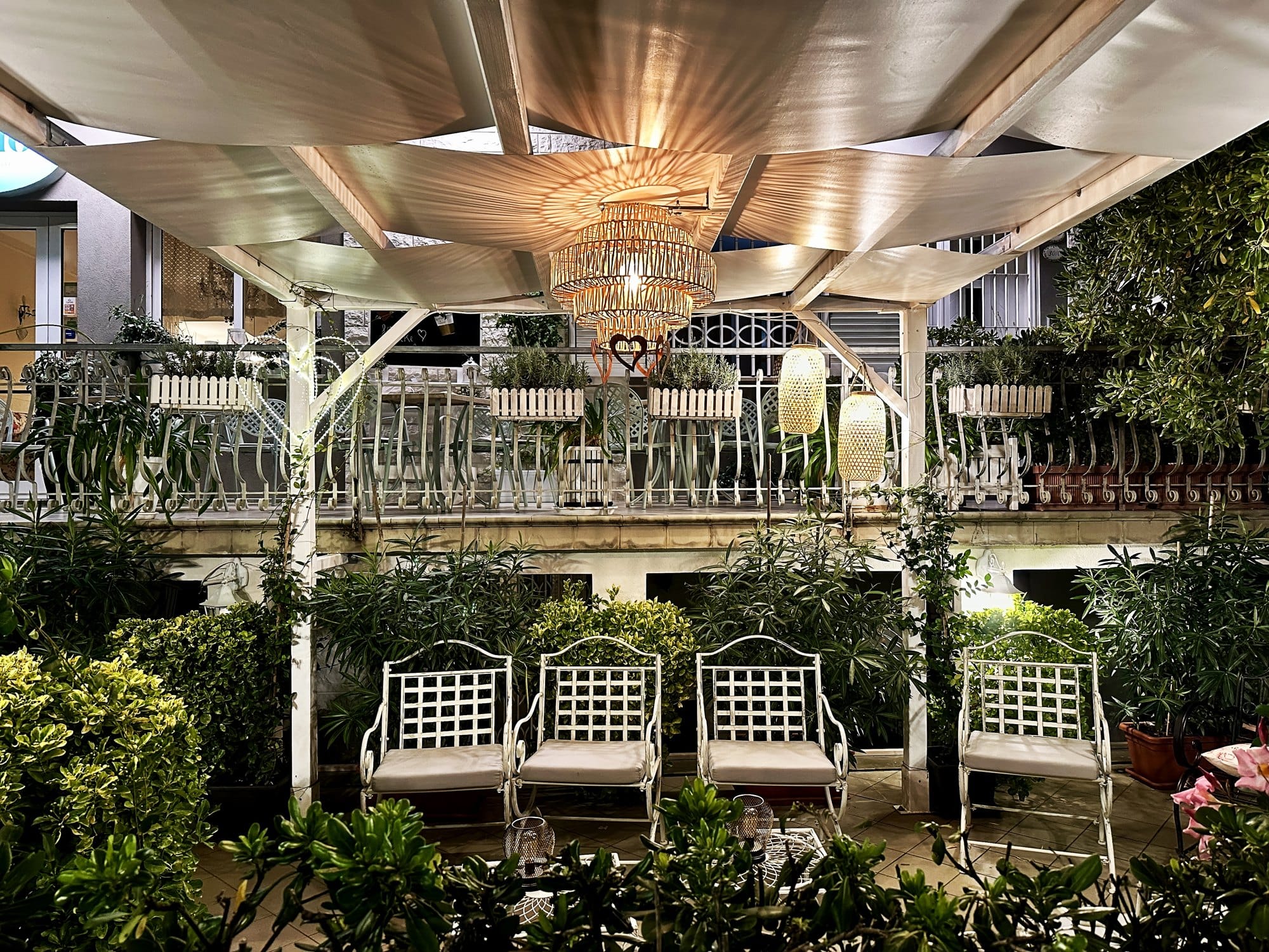 Cozy Outdoor Living Space With Comfortable Chairs, Warm Lamps Light And Green Plants in Garden