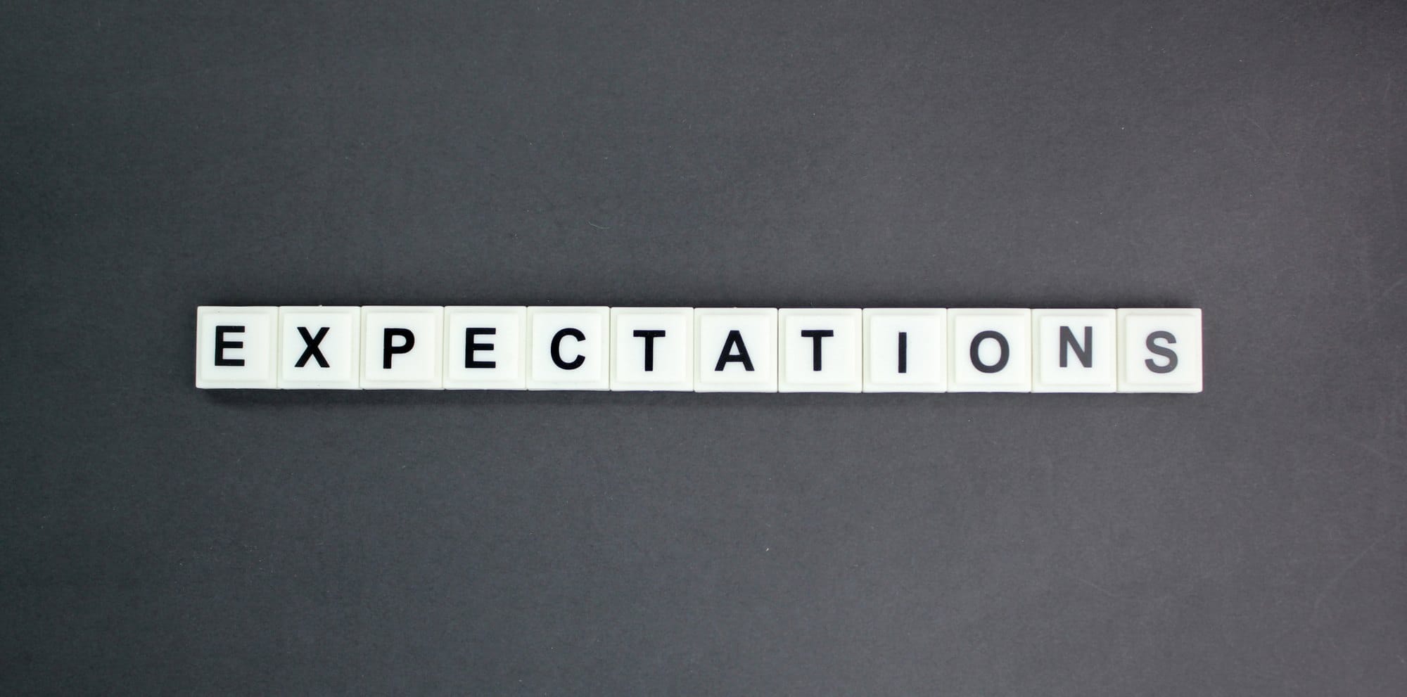 Expectations Message on Tiles Against a Dark Backdrop